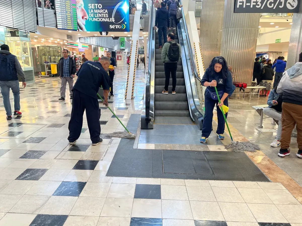 Personal de Grupo Lyon trapeando junto a una escalera eléctrica del aeropuerto