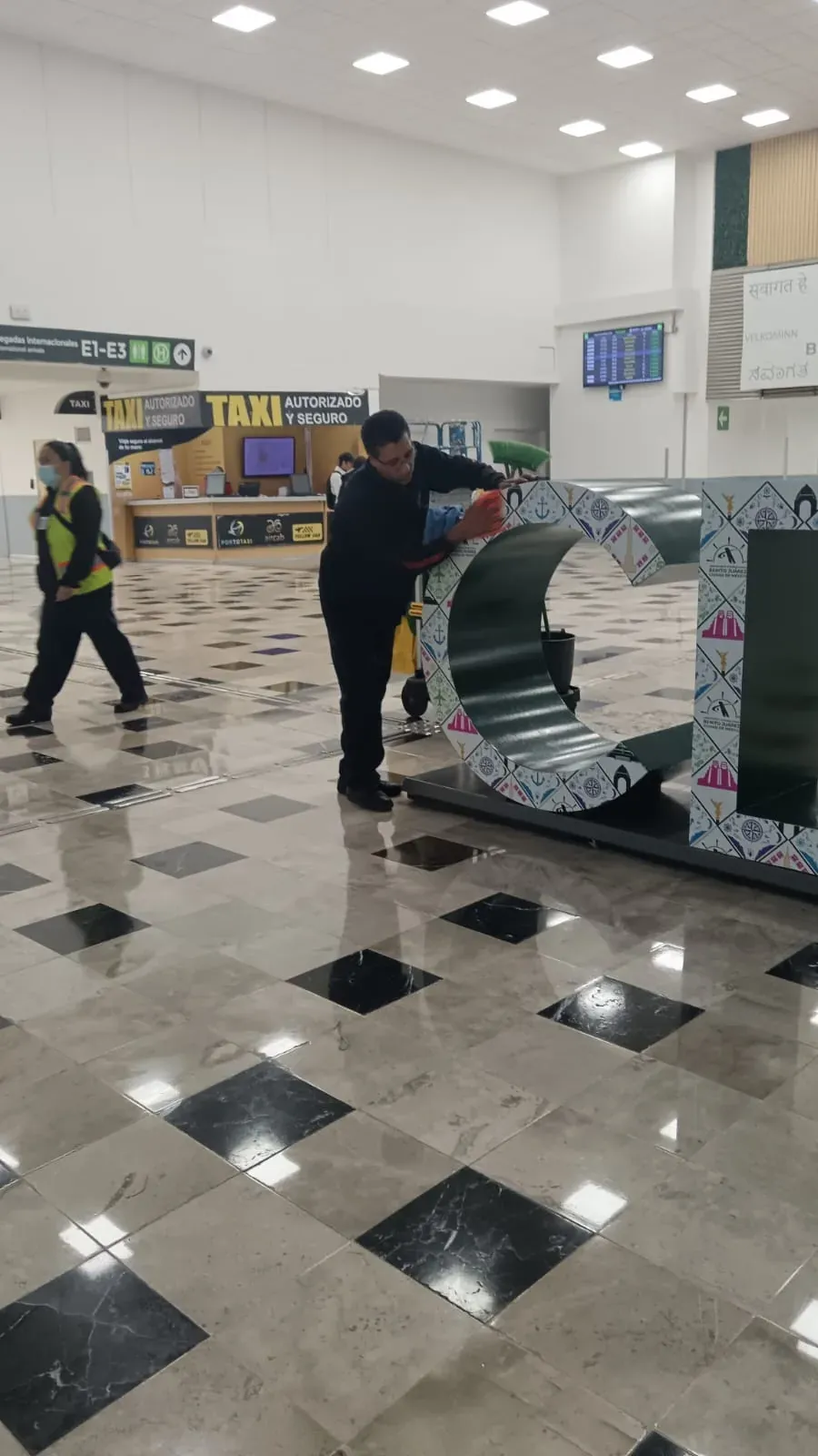 Integrante de Grupo Lyon limpiando junto a una escultura en la terminal del aeropuerto