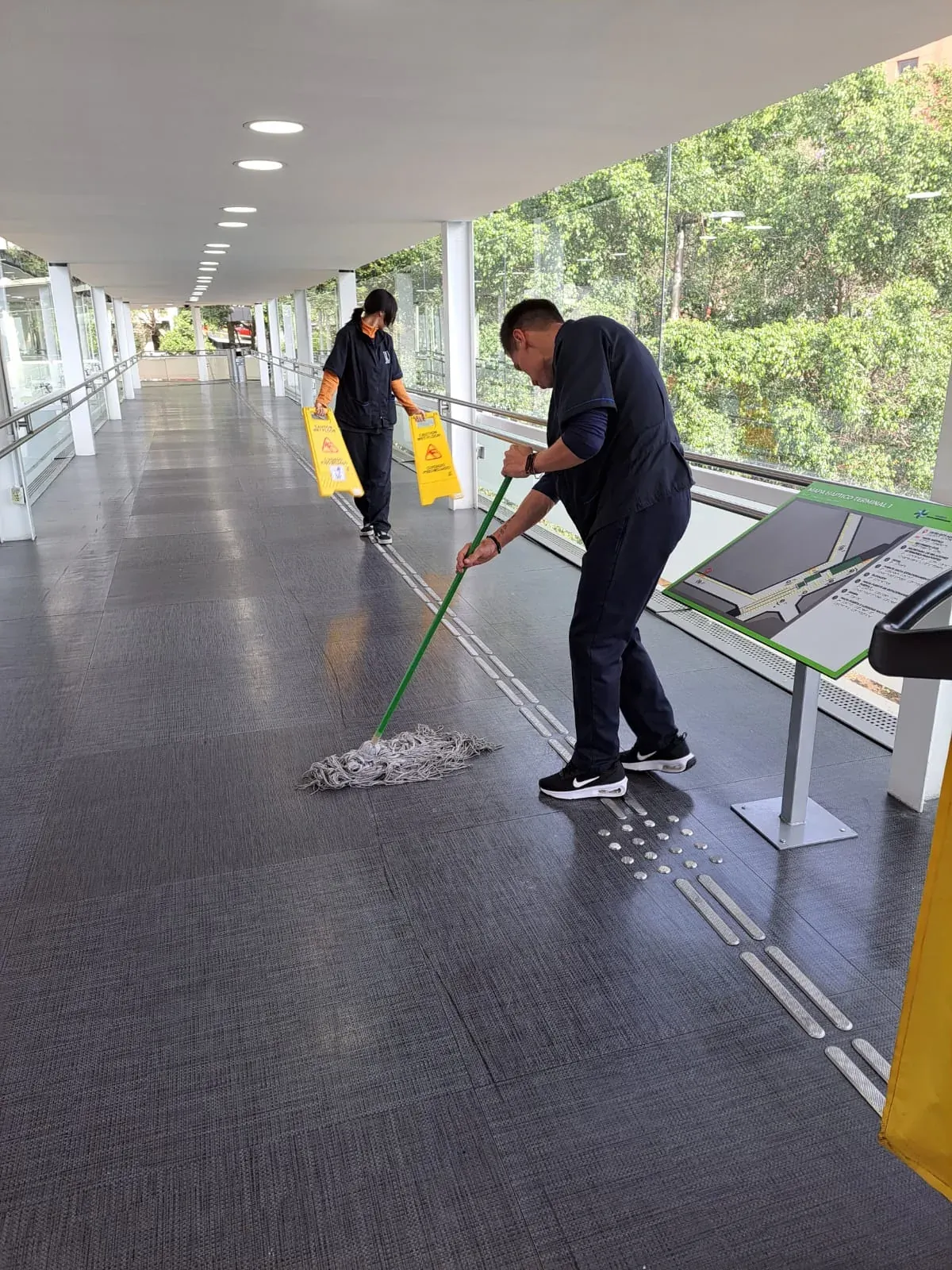 Personal de Grupo Lyon trapeando la pasarela peatonal del Aeropuerto Internacional de la Ciudad de México