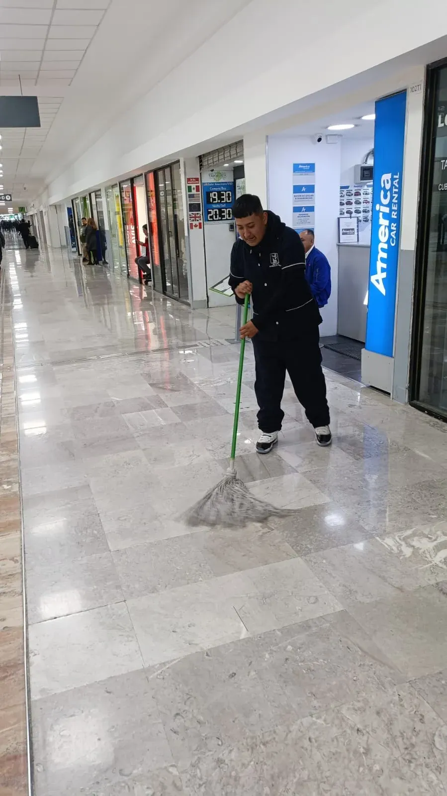 Integrante de Grupo Lyon trapeando un pasillo comercial del aeropuerto