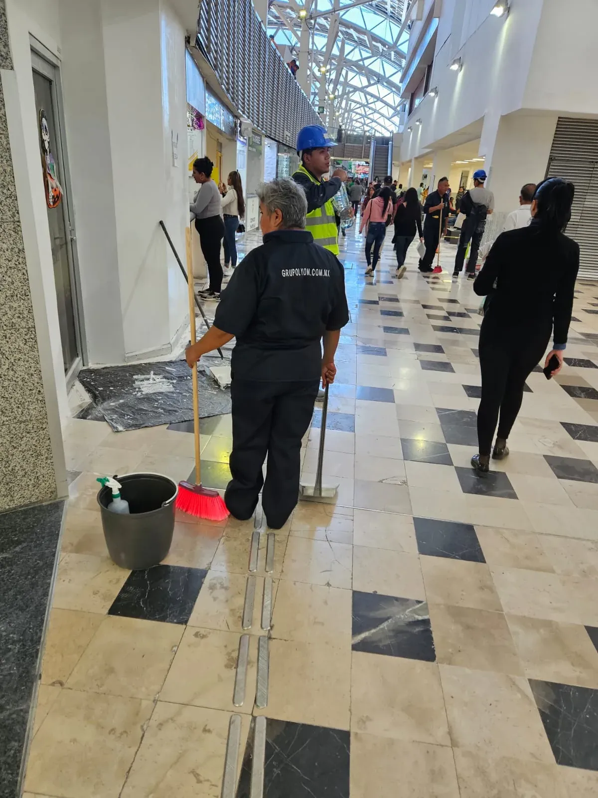 Integrante de Grupo Lyon de espaldas con el uniforme GRUPOLYON.COM.MX en un pasillo del aeropuerto