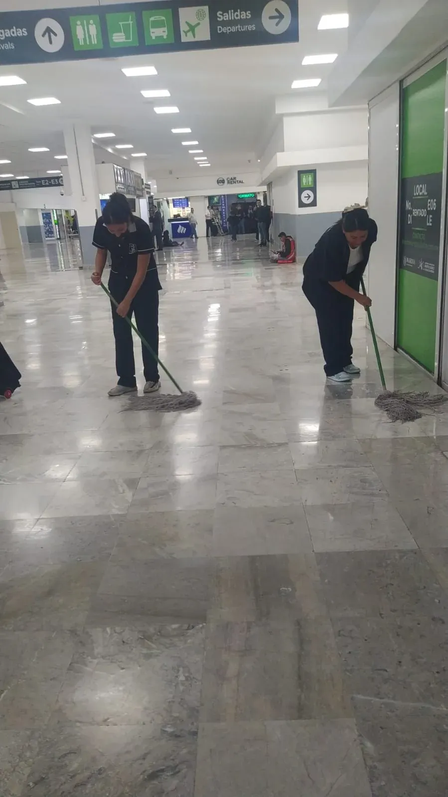 Dos integrantes de Grupo Lyon trapeando un área amplia del aeropuerto