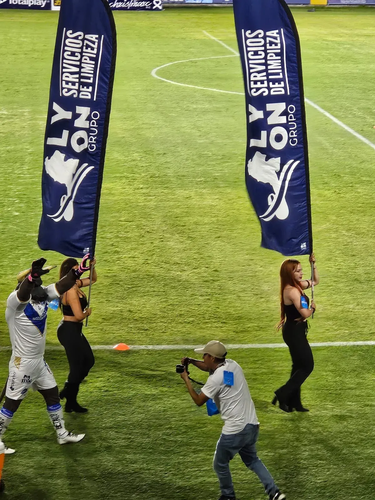 Banderas de Grupo Lyon Servicios de Limpieza en la cancha de un estadio durante un evento
