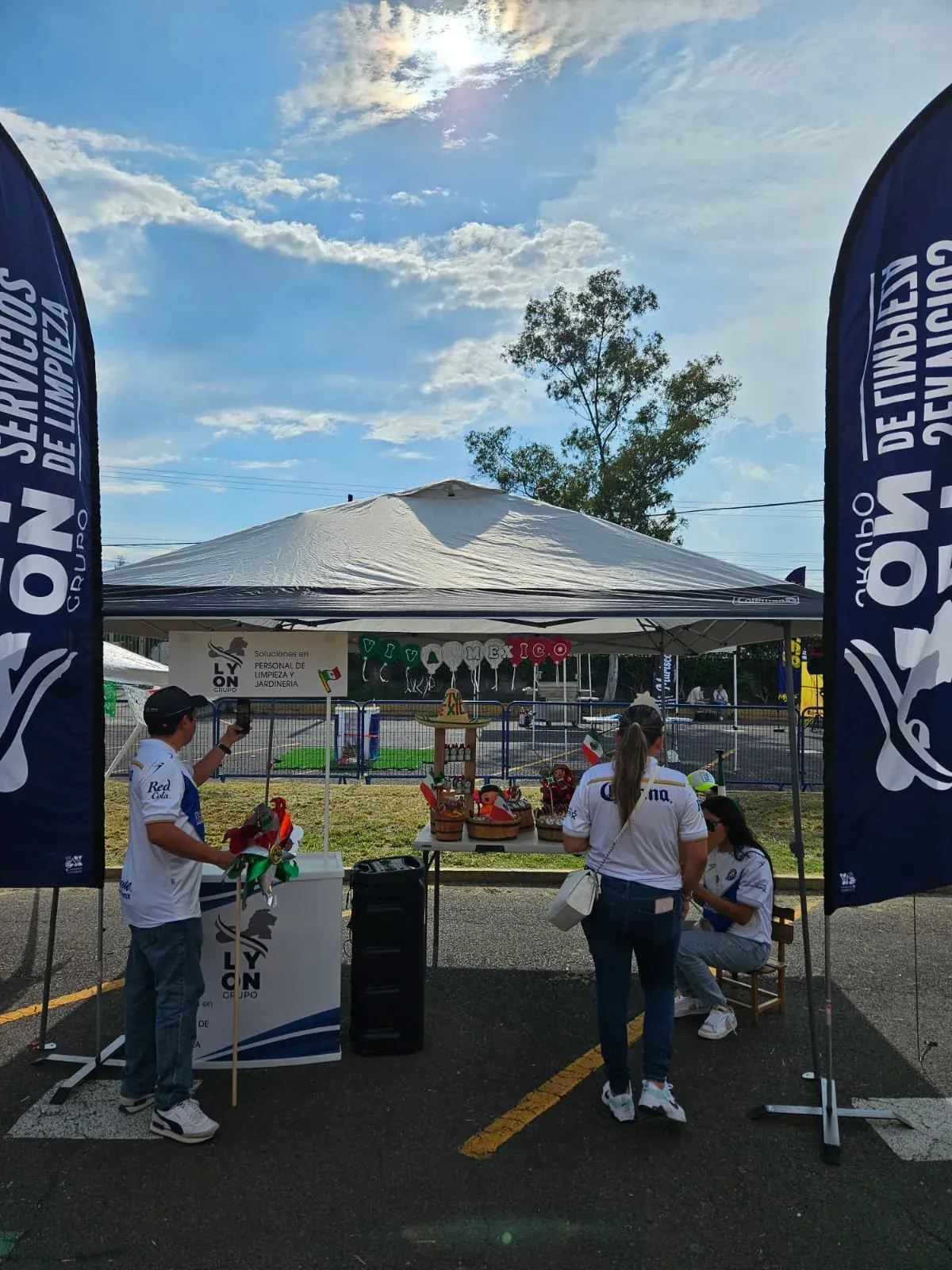 Stand de Grupo Lyon bajo carpa con banderas de Servicios de Limpieza